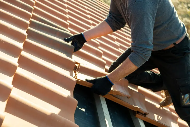 Roofer fitting replacement tiles during a roof repair in Wetherby